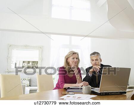 Stock Photo - Woman sitting at table with financial advisor. Fotosearch