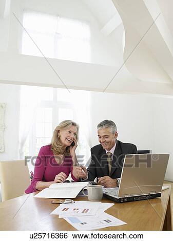 Stock Photograph - Woman sitting at table with financial advisor. Fotosearch