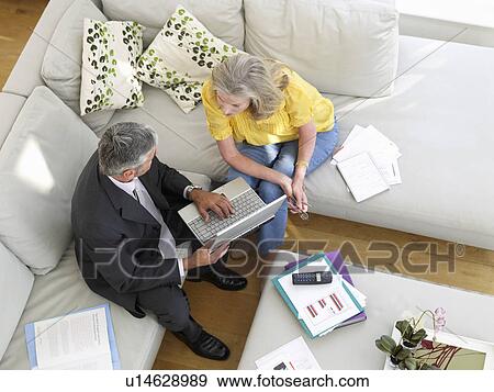 Stock Photo - Woman sitting on sofa with financial advisor elevated view. Fotosearch