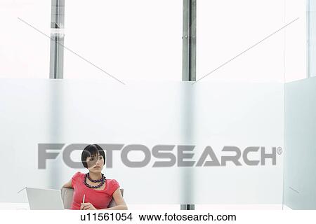 Picture - Woman sitting with laptop in modern cubicle. Fotosearch