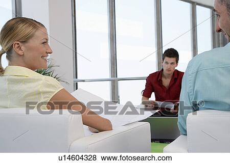 Stock Photo - Woman smiling at man in waiting room back view. Fotosearch
