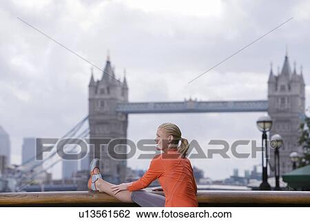 Stock Image - Woman stretching in front of Tower Bridge England London. Fotosearch