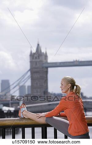 Stock Image - Woman stretching in front of Tower Bridge England London. Fotosearch