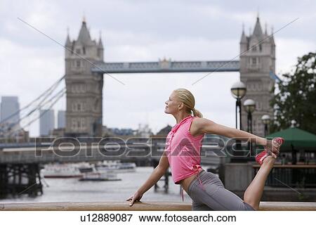 Stock Photo - Woman stretching in front of Tower Bridge England London. Fotosearch
