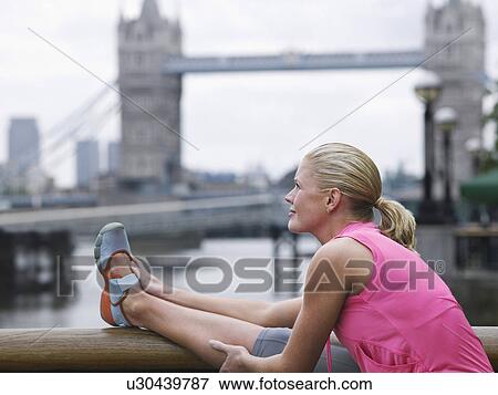Stock Photo - Woman stretching in front of Tower Bridge England London. Fotosearch