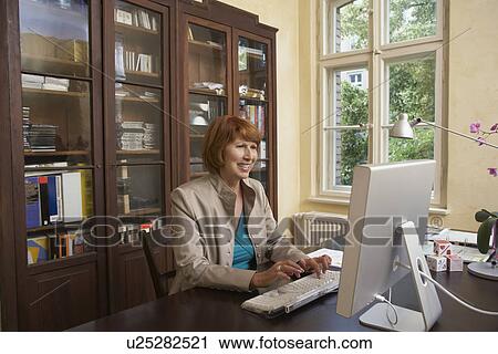 Woman using computer in living room View Large Photo Image Stock Image - Woman using computer in living room. Fotosearch