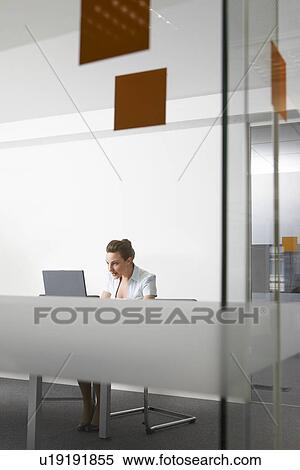 Stock Photography - Woman using laptop behind glass door. Fotosearch
