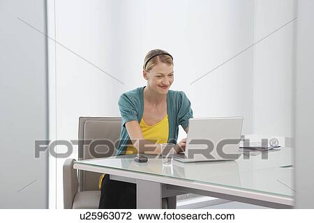 Stock Image - Woman using laptop in office. Fotosearch