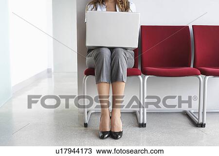 Woman using laptop on chairs in corridor low section View Large Photo Image Stock Image - Woman using laptop on chairs in corridor low section. Fotosearch