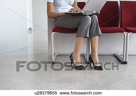 Woman using laptop on chairs in corridor low section View Large Photo Image Stock Photography - Woman using laptop on chairs in corridor low section. Fotosearch