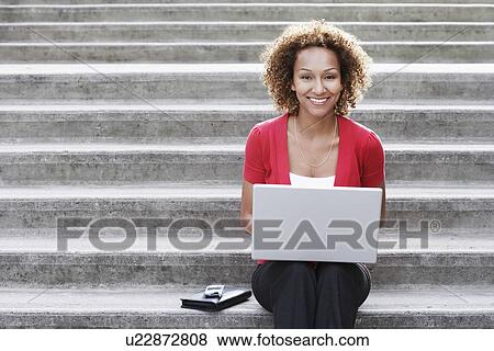 Stock Photo - Woman using laptop on steps portrait. Fotosearch