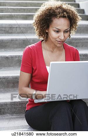 Stock Image - Woman using laptop on steps. Fotosearch