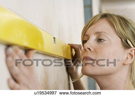 Stock Photo - Woman using spirit level close-up. Fotosearch