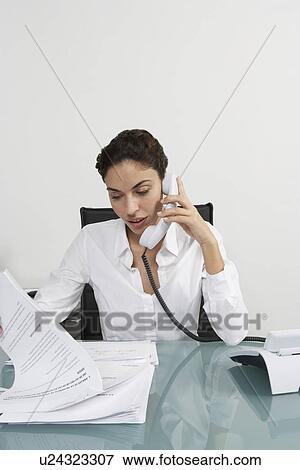 Woman using telephone at desk in office View Large Photo Image Stock Photo - Woman using telephone at desk in office. Fotosearch