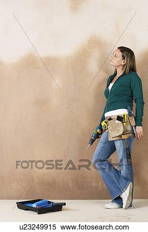 Woman with toolbelt and drill leaning against wall View Large Photo Image Stock Photography - Woman with toolbelt and drill leaning against wall. Fotosearch
