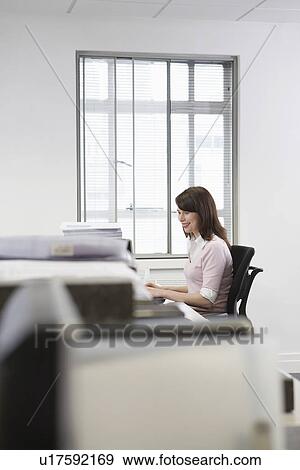 Stock Photo - Woman working at desk in office side view. Fotosearch