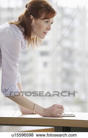 Woman writing at desk in office View Large Photo Image Stock Photo - Woman writing at desk in office. Fotosearch