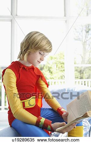 Young boy (7-9) in superman costume sitting and reading indoors View Large Photo Image Stock Photography - Young boy (7-9) in superman costume sitting and reading indoors. Fotosearch