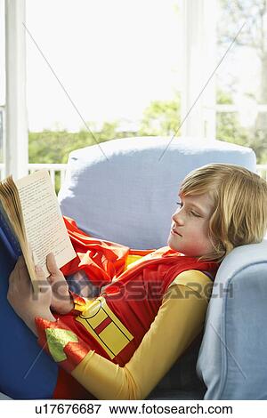 Young boy (7-9) sitting in armchair reading wearing superhero costume side view View Large Photo Image Stock Photo - Young boy (7-9) sitting in armchair reading wearing superhero costume side view. Fotosearch