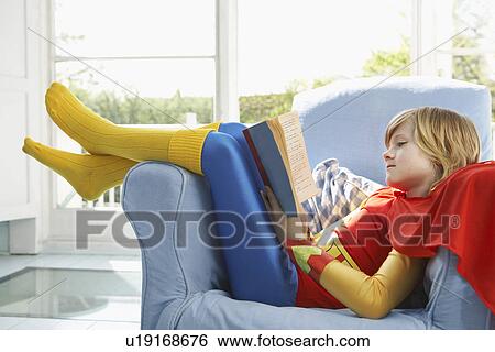 Young boy (7-9) sitting in armchair reading wearing superhero costume side view View Large Photo Image Stock Photograph - Young boy (7-9) sitting in armchair reading wearing superhero costume side view. Fotosearch