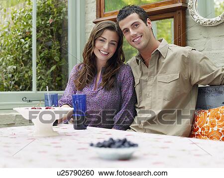 Young couple sitting at verandah table smiling portrait View Large Photo Image Stock Image - Young couple sitting at verandah table smiling portrait. Fotosearch