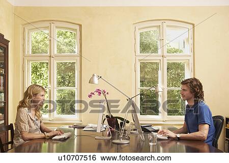 Young couple using computers across table in living room View Large Photo Image Stock Photograph - Young couple using computers across table in living room. Fotosearch