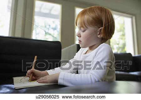 Stock Photography - Young girl (5-6) drawing at desk. Fotosearch