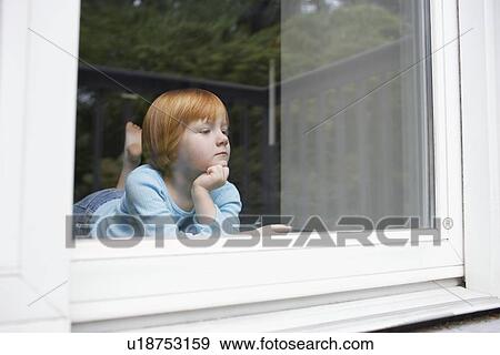 Young girl (5-6) indoors looking through window View Large Photo Image Stock Photo - Young girl (5-6) indoors looking through window. Fotosearch
