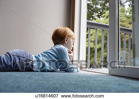 Young girl (5-6) lying on carpet looking through balcony door View Large Photo Image Stock Photo - Young girl (5-6) lying on carpet looking through balcony door. Fotosearch