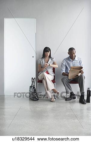 Young man and woman waiting on chairs in corridor View Large Photo Image Picture - Young man and woman waiting on chairs in corridor. Fotosearch