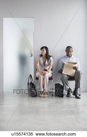 Young man and woman waiting on chairs in corridor third person visible through translucent door View Large Photo Image Stock Photography - Young man and woman waiting on chairs in corridor third person visible through translucent door. Fotosearch