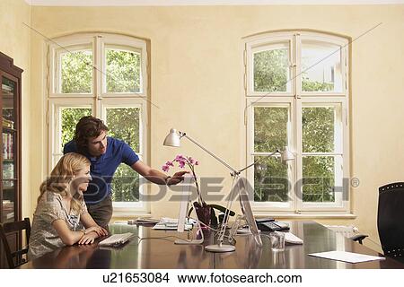 Young man helping young woman working on computer in living room View Large Photo Image Picture - Young man helping young woman working on computer in living room. Fotosearch