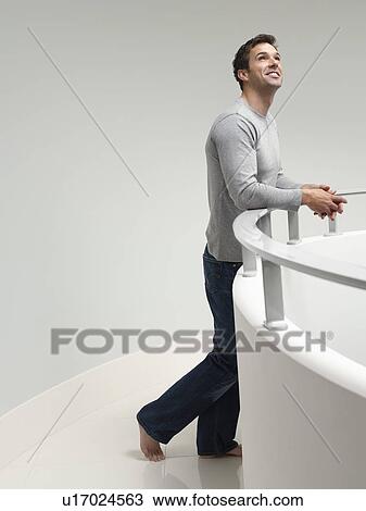 Young man leaning on railing indoors looking up View Large Photo Image Stock Image - Young man leaning on railing indoors looking up. Fotosearch
