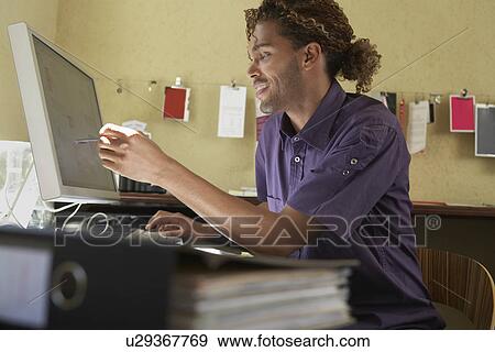 Young man pointing at computer screen in office View Large Photo Image Stock Photo - Young man pointing at computer screen in office. Fotosearch