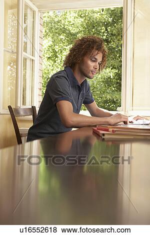 Young man reading in living room near open window View Large Photo Image Stock Photo - Young man reading in living room near open window. Fotosearch