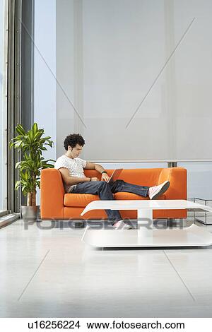 Young man reading newspaper in reception room View Large Photo Image Picture - Young man reading newspaper in reception room. Fotosearch
