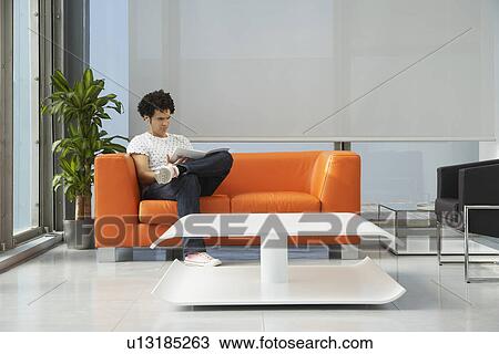 Young man reading newspaper in reception room View Large Photo Image Stock Image - Young man reading newspaper in reception room. Fotosearch
