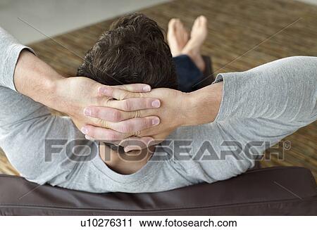 Young man sitting indoors with hands behind head close-up back view View Large Photo Image Stock Image - Young man sitting indoors with hands behind head close-up back view. Fotosearch