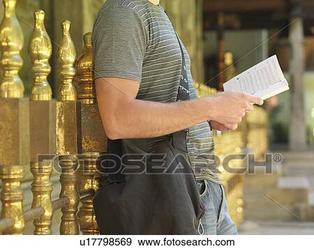 Young man standing by railing reading book side view mid section View Large Photo Image Stock Photo - Young man standing by railing reading book side view mid section. Fotosearch