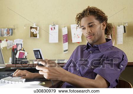 Young man using mobile phone in office View Large Photo Image Stock Photo - Young man using mobile phone in office. Fotosearch