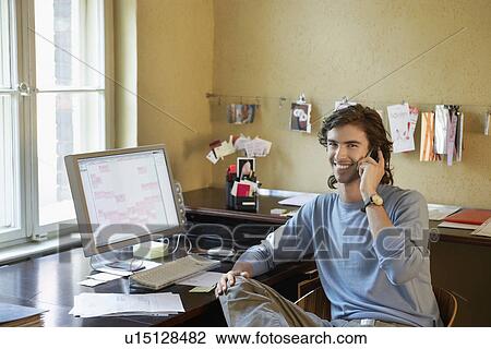 Young man using phone in office View Large Photo Image Stock Image - Young man using phone in office. Fotosearch