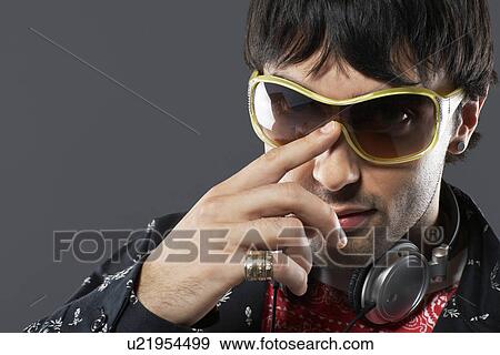 Stock Photo - Young man wearing sunglasses and headphones portrait close-up. Fotosearch