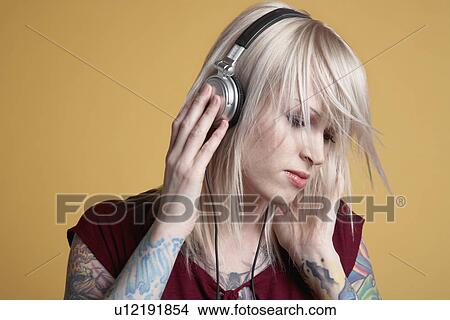 Young tattooed woman listening to music on headphones View Large Photo Image Picture - Young tattooed woman listening to music on headphones. Fotosearch