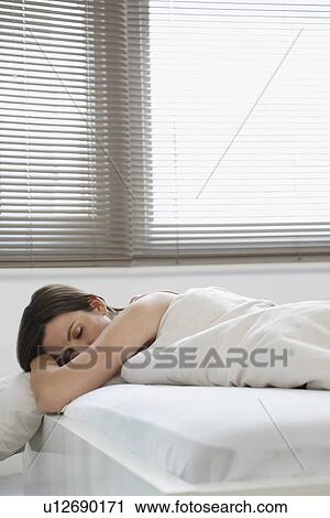 Stock Image - Young woman asleep in bed. Fotosearch