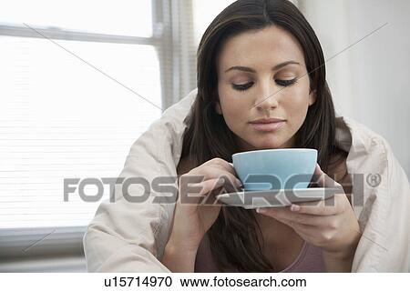 Young woman drinking tea in bed View Large Photo Image Stock Image - Young woman drinking tea in bed. Fotosearch
