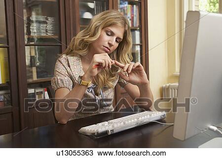 Young woman filing fingernails over computer in living room View Large Photo Image Stock Image - Young woman filing fingernails over computer in living room. Fotosearch