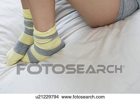 Picture - Young woman in underwear on bed low section. Fotosearch