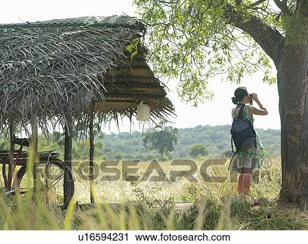 Young woman looking through binoculars bicycle under thatched roof View Large Photo Image Stock Image - Young woman looking through binoculars bicycle under thatched roof. Fotosearch