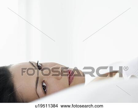 Picture - Young woman lying down looking away close-up. Fotosearch