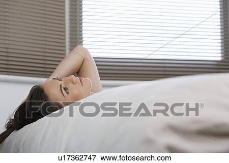 Stock Photo - Young woman lying in bed looking up. Fotosearch